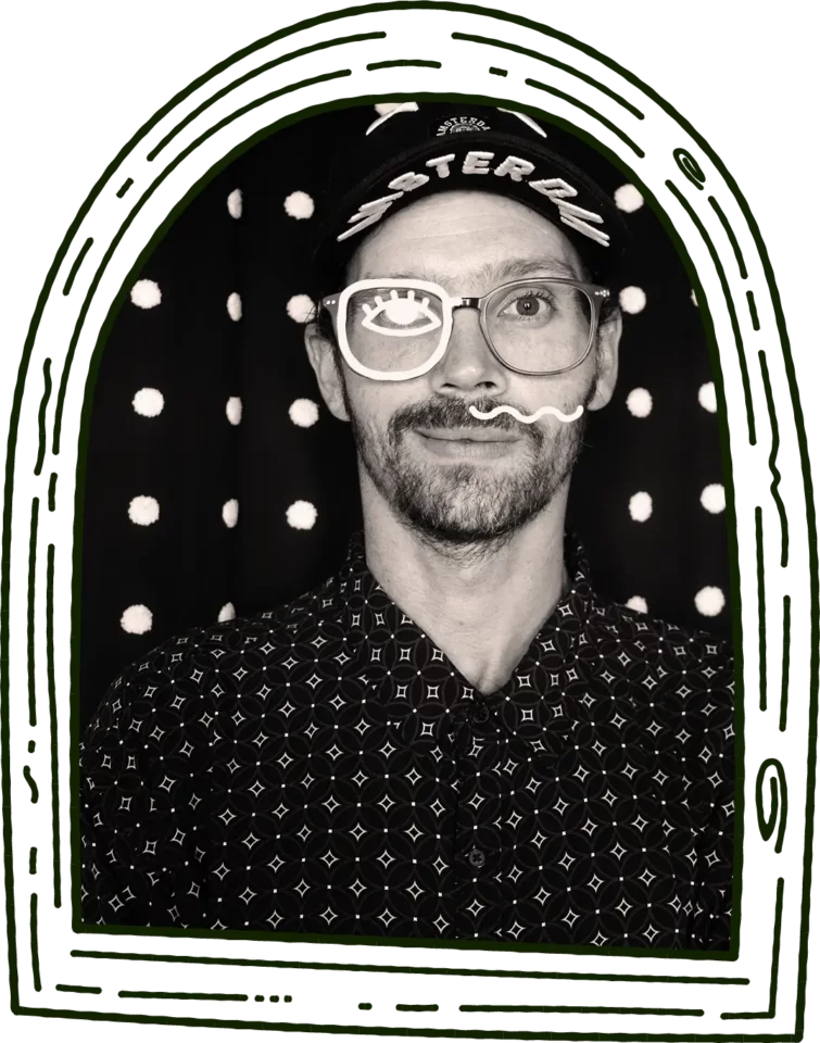 black and white photo of illustrator and moonface co-founder, patrick, in a dark green line illustration of an arched wooden frame. man in mid-30s wears black cap and black patterned button-up shirt. animated images of half glasses and half a moustache flash on his face, both elements taken from the moonface design co. original logo.